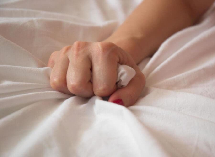 Hand gripping on a fabric, most likely a sheet or blanket.