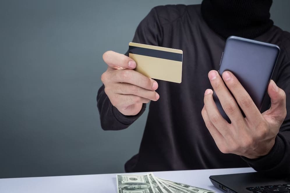 scammer holding bank card and phone