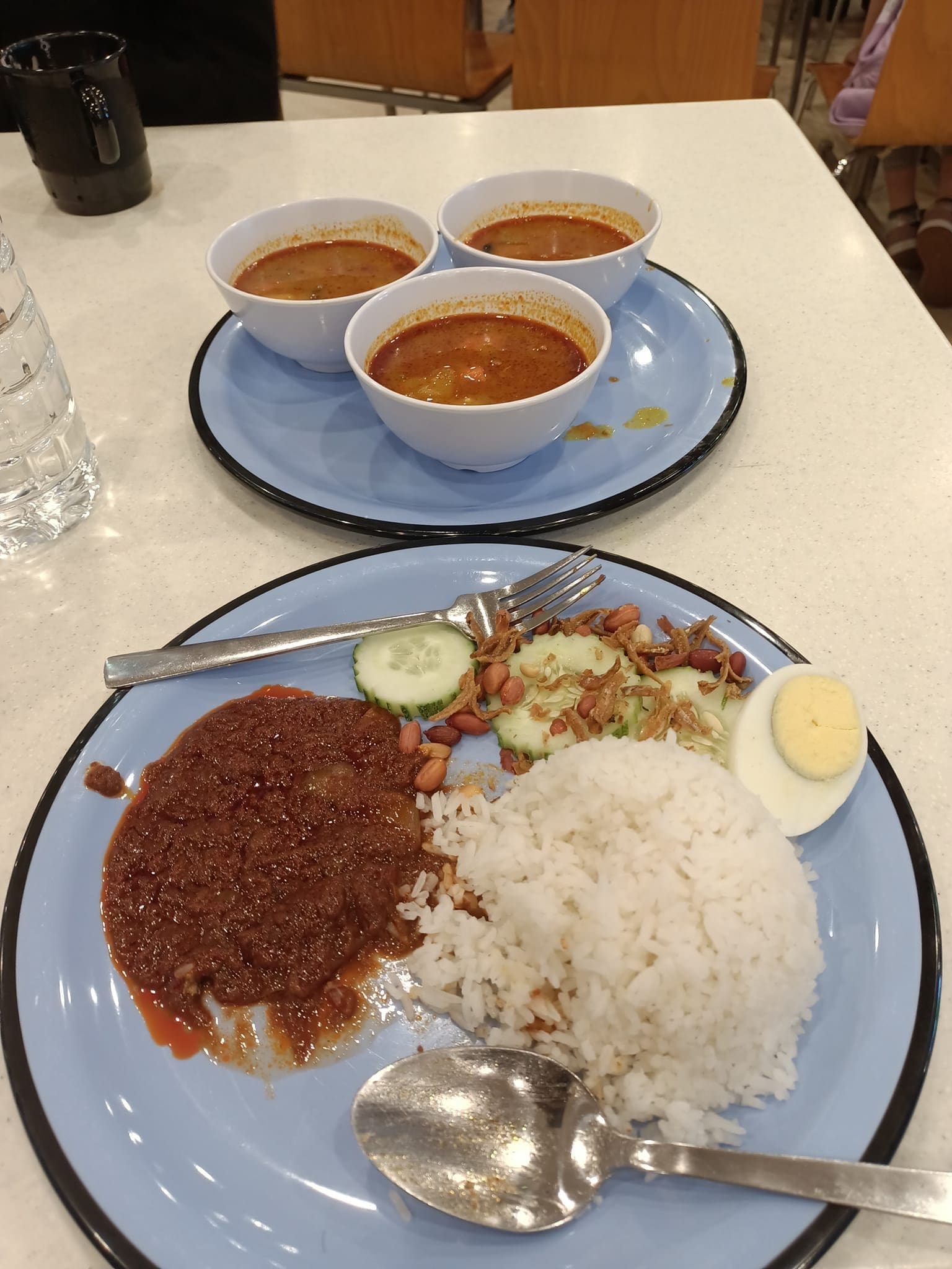 A plate of nasi lemak and 3 bowls of curry