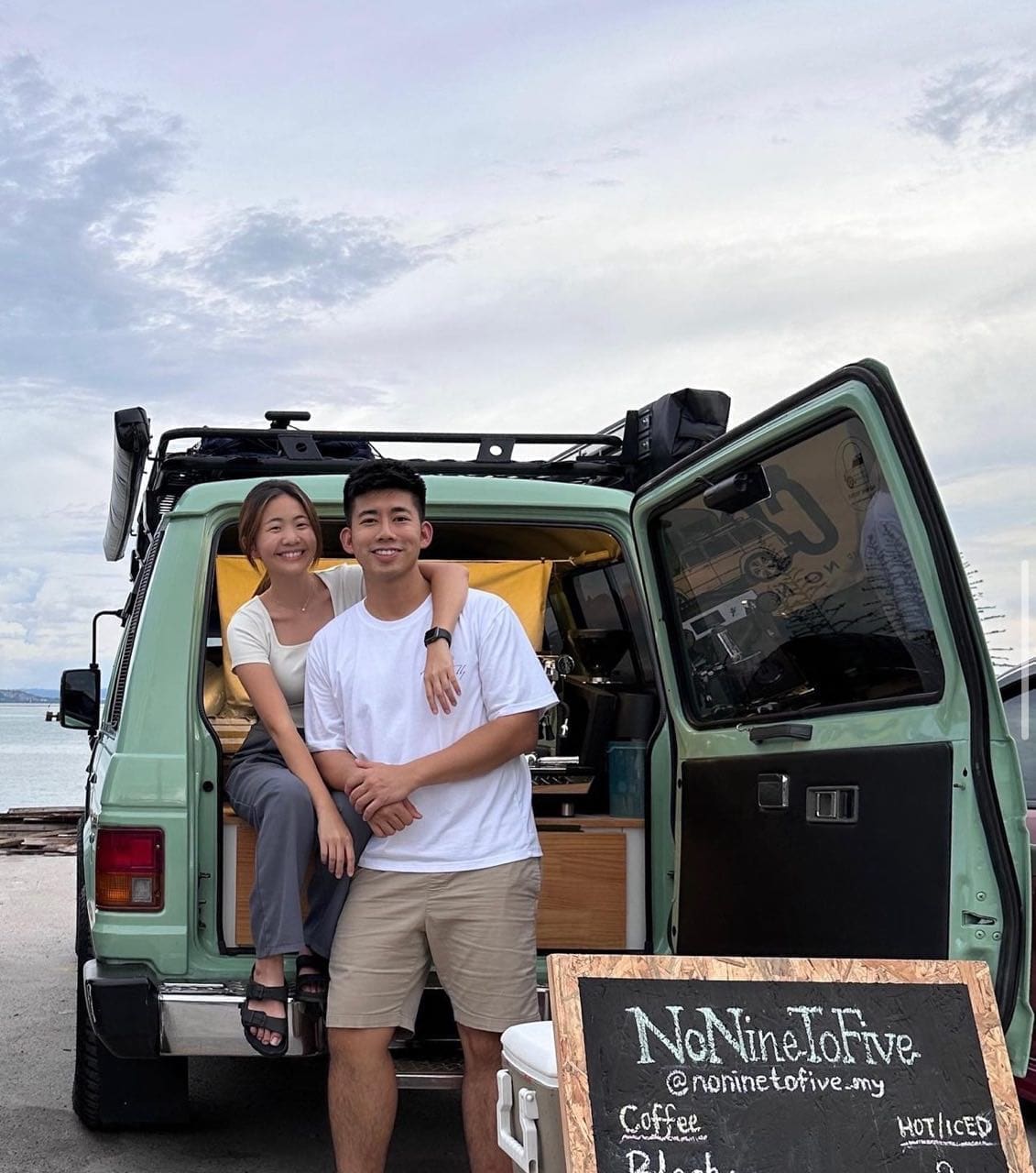 Nik and Jing sitting on their car