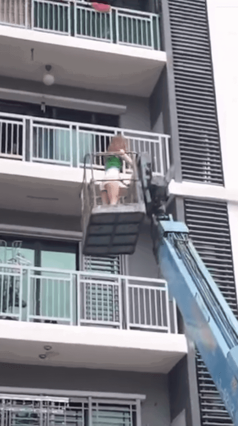 msian woman using crane to enter her home through balcony