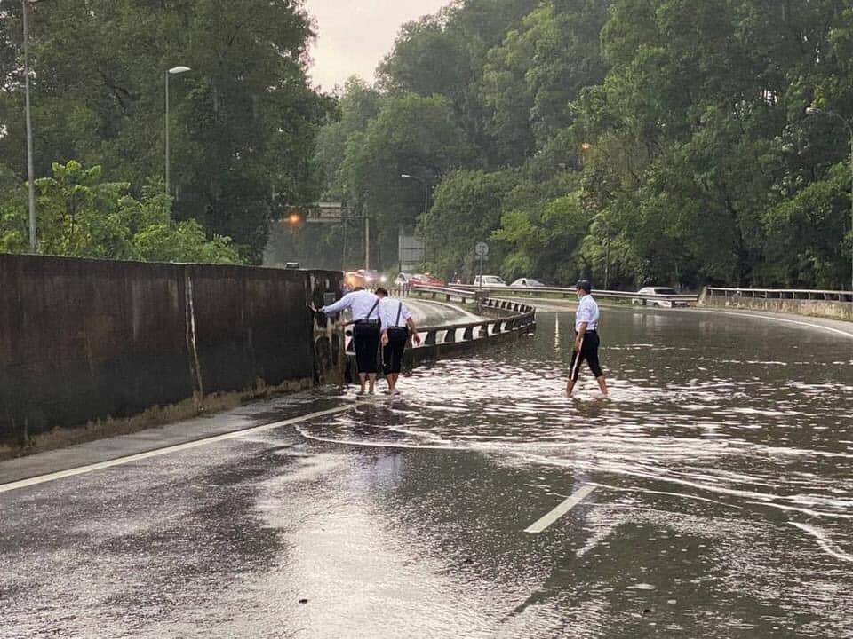 Traffic police get down and dirty to unclog drain along the nilai highway