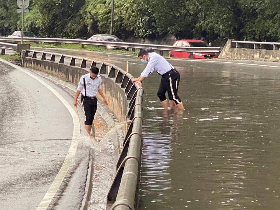 Traffic police get down and dirty to unclog drain along the nilai highway