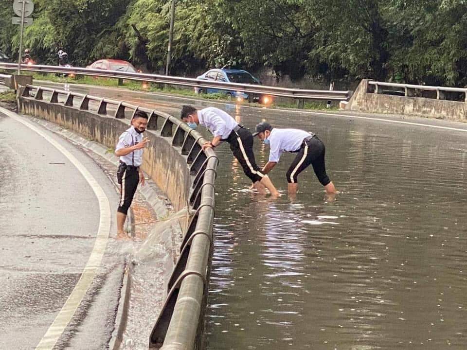Traffic police get down and dirty to unclog drain along the nilai highway