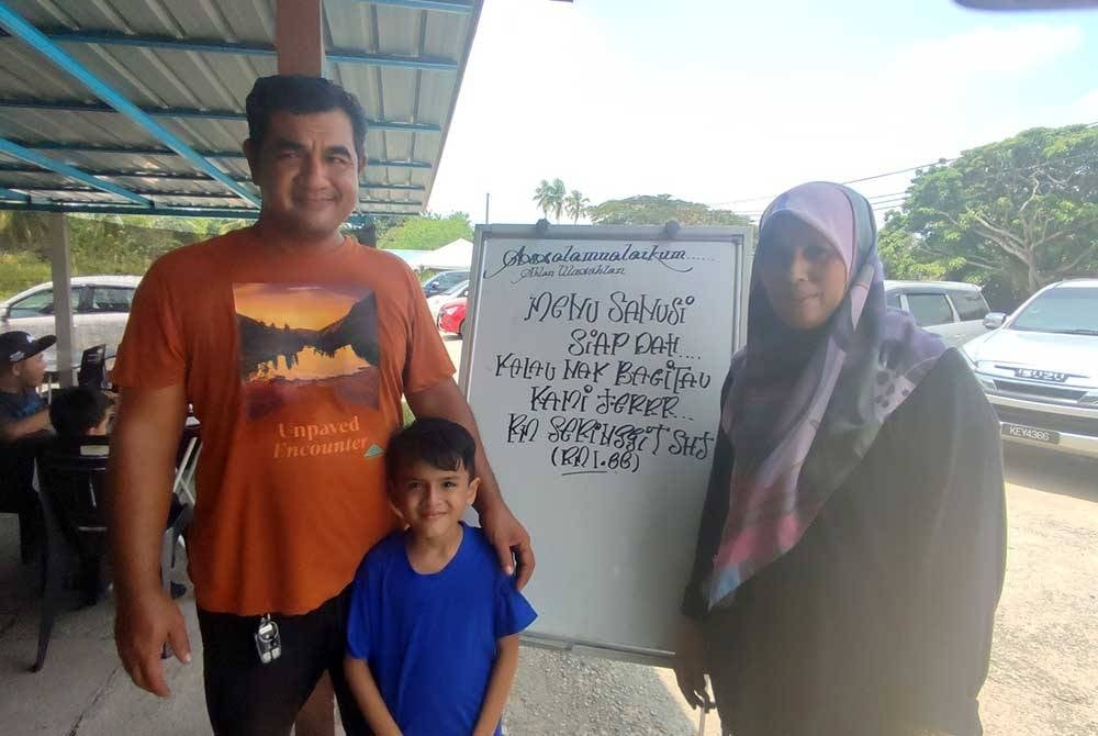 Msian stall owners standing beside their sanusi menu