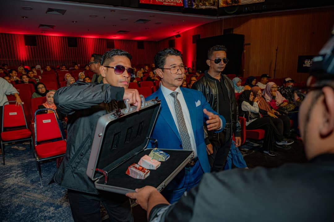 Azmi zainal's representative opened a suitcase with his products to another person at a show.