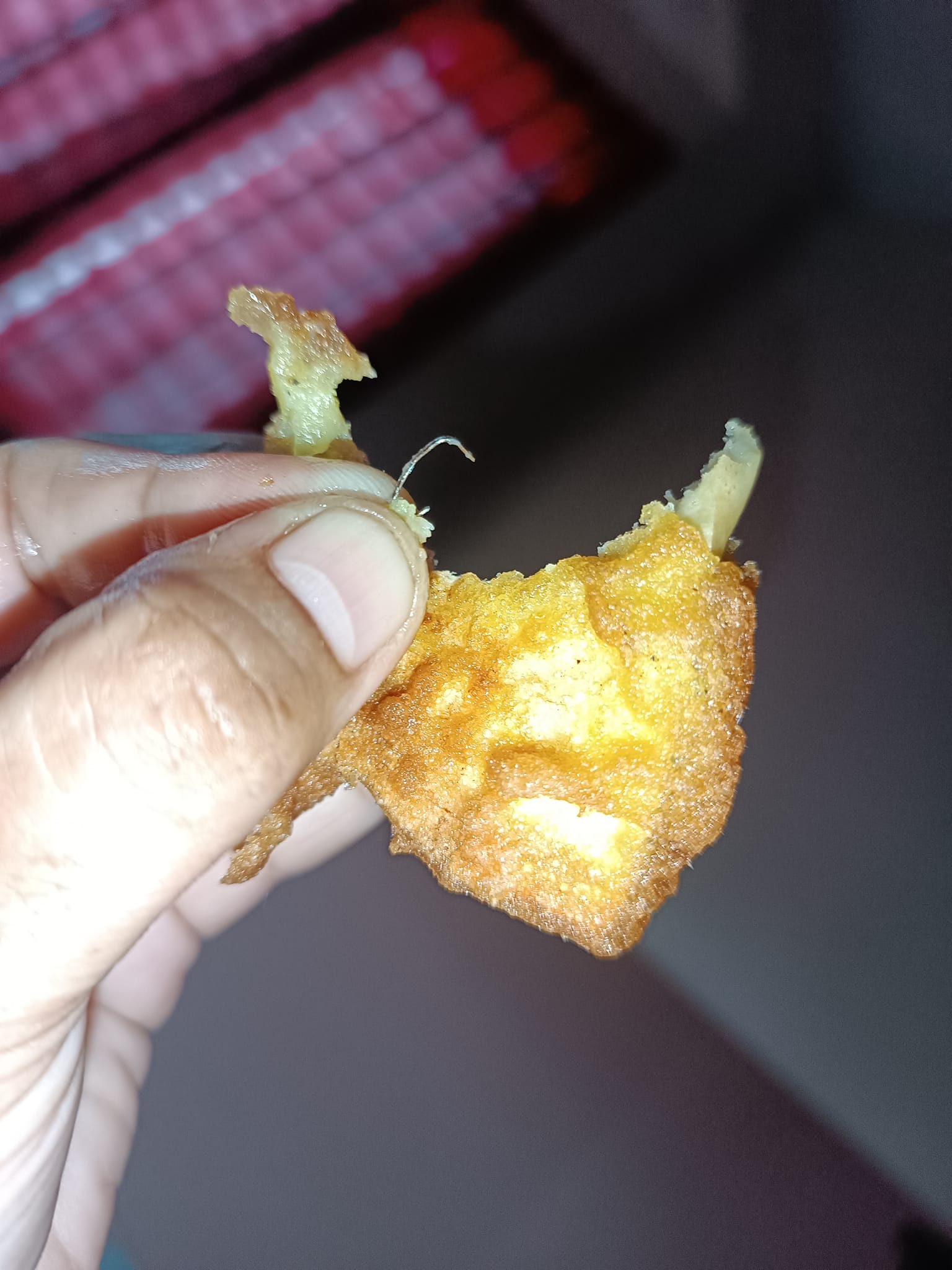 A msian woman showing a staple pin that she found inside the jackfruit fritters she bought from a stall.