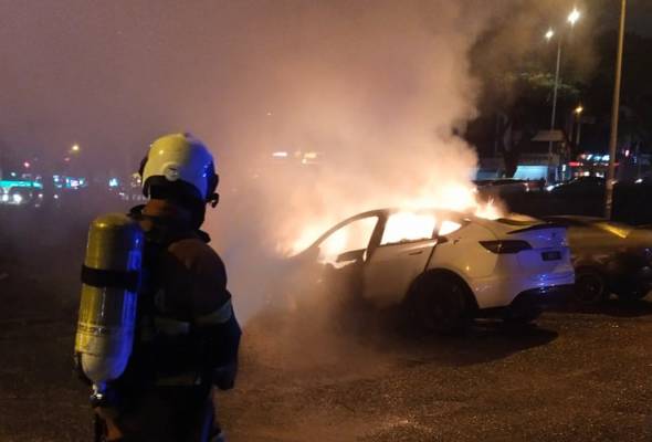Firefighter putting out the fire that was burning down the tesla car