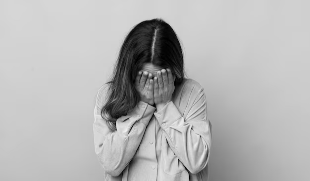 Girl hides her face with her hands