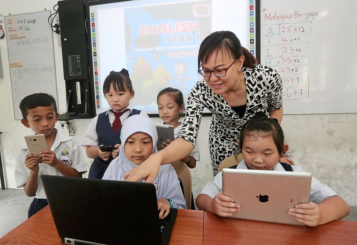 Teacher, leong wai ting teaching her students by using it gadgets at a classroom.