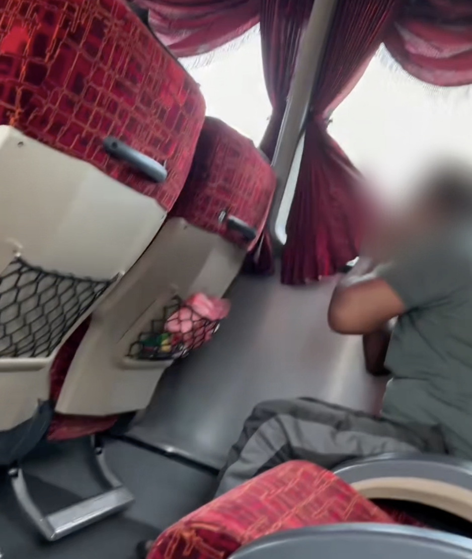 Passenger wiping mouth on bus curtain
