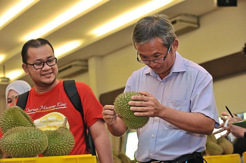 2 mans observing durian attentively