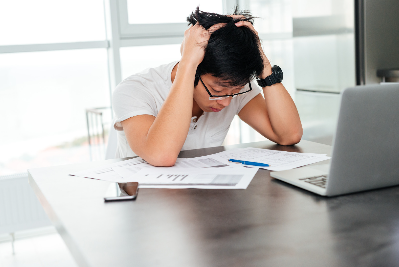 Asian man holding his head in despair