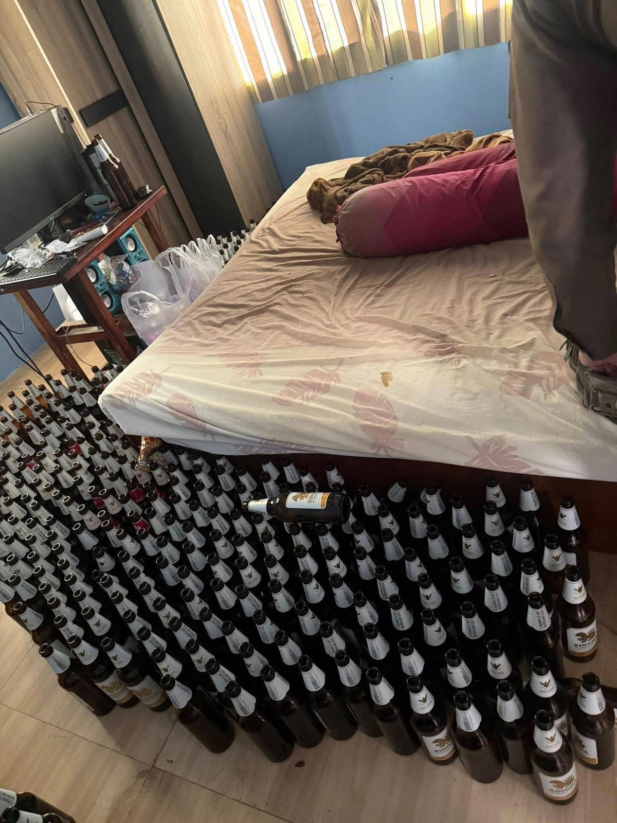 Beer bottles being lined up in Thai man's room