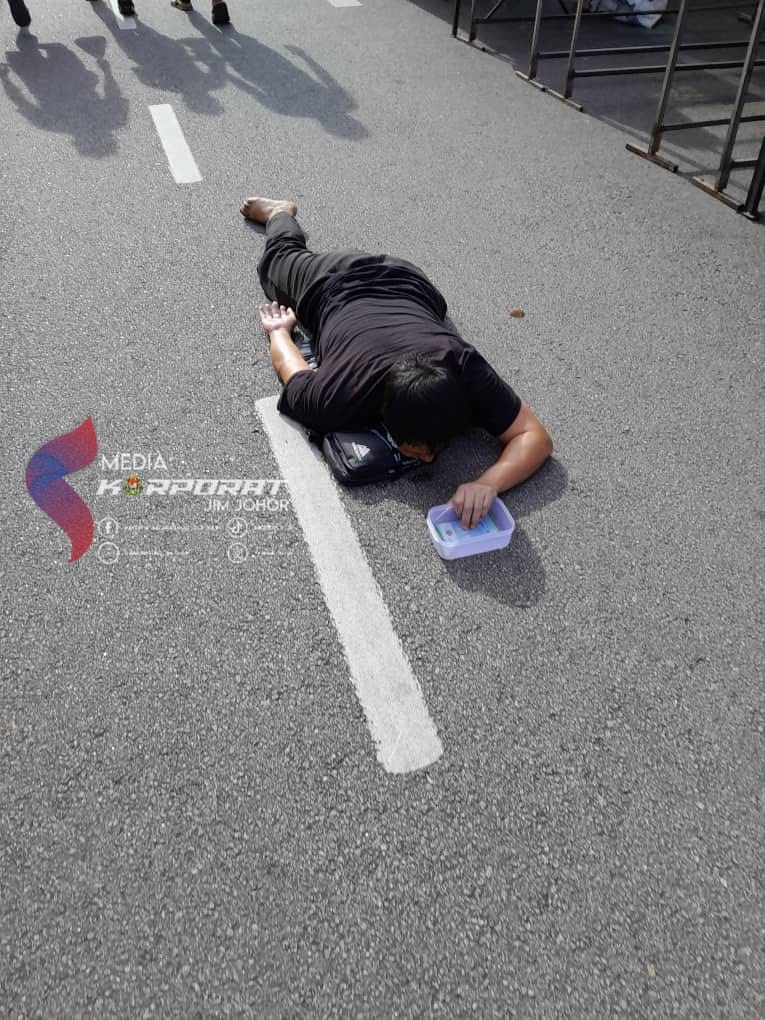 Beggar laying on road at night market in jb