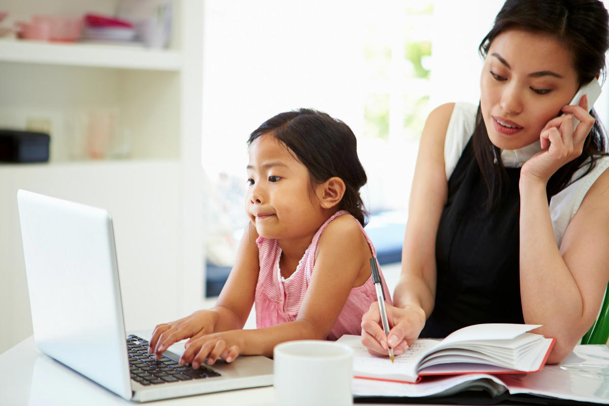 Asian mom with her daughter while being busy with work.