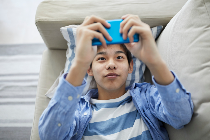 boy lying on the couch and using phone