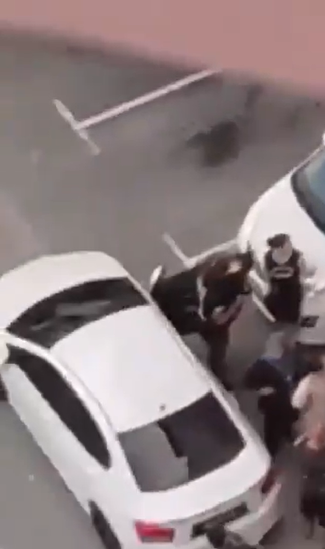 Bystanders watch woman break car window