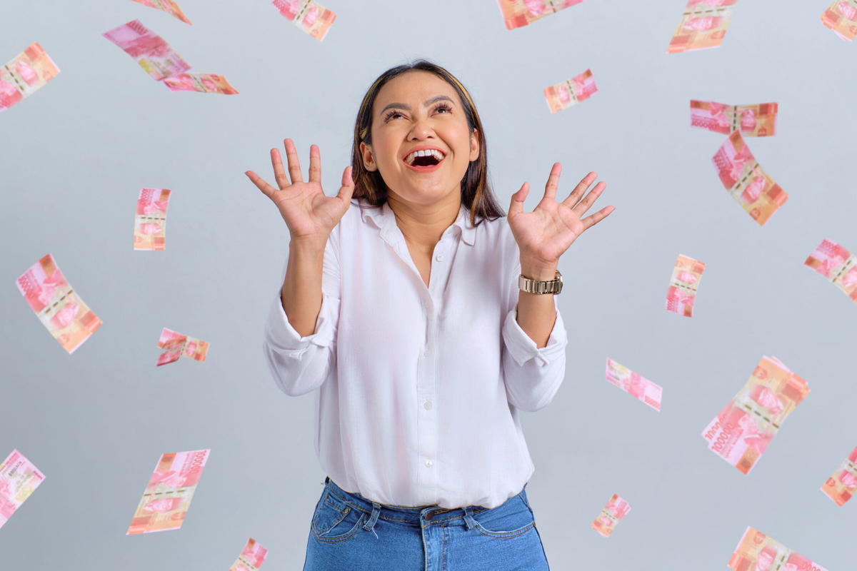 Happy woman with money raining down