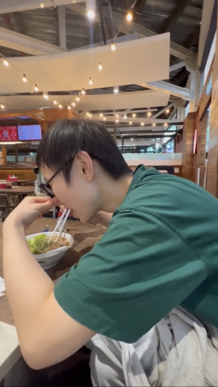 China woman eats asam laksa while pinching her nose