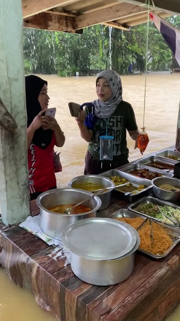 The customers patiently waiting in the floodwater while the seller packed their food.  