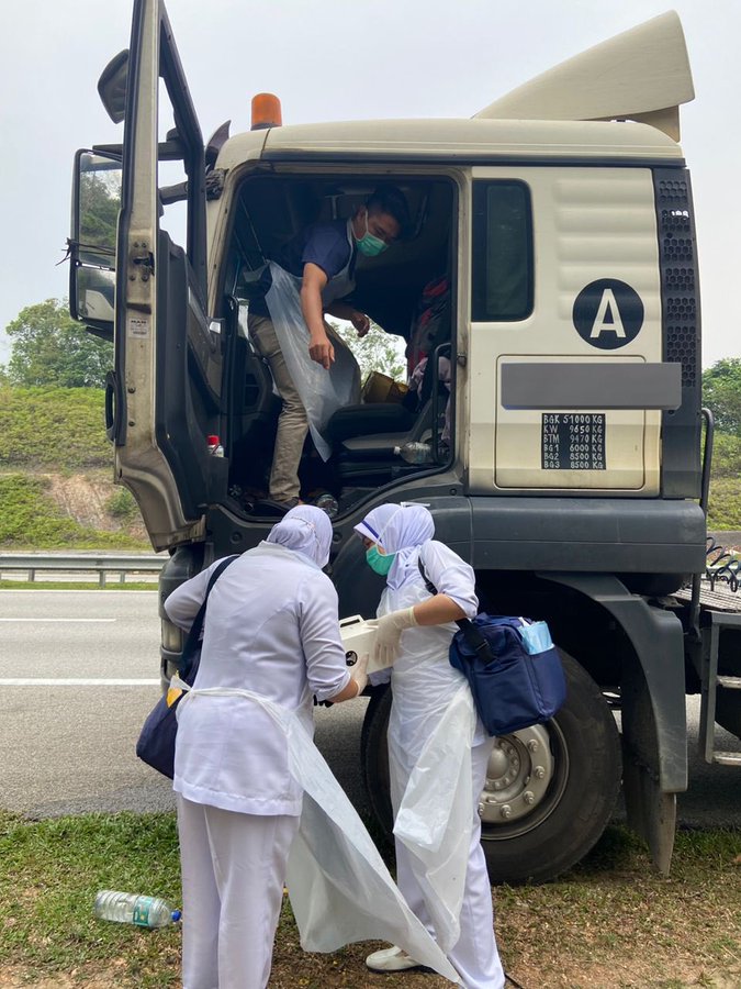 Msian doctor inside the lorry helping the pregnant woman while assisted by two nurses at road side