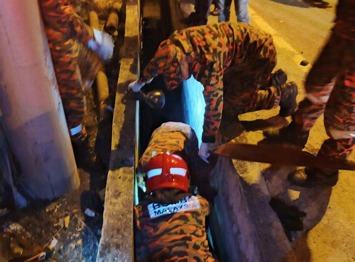 Firefighters carrying body of man from drain in Penang
