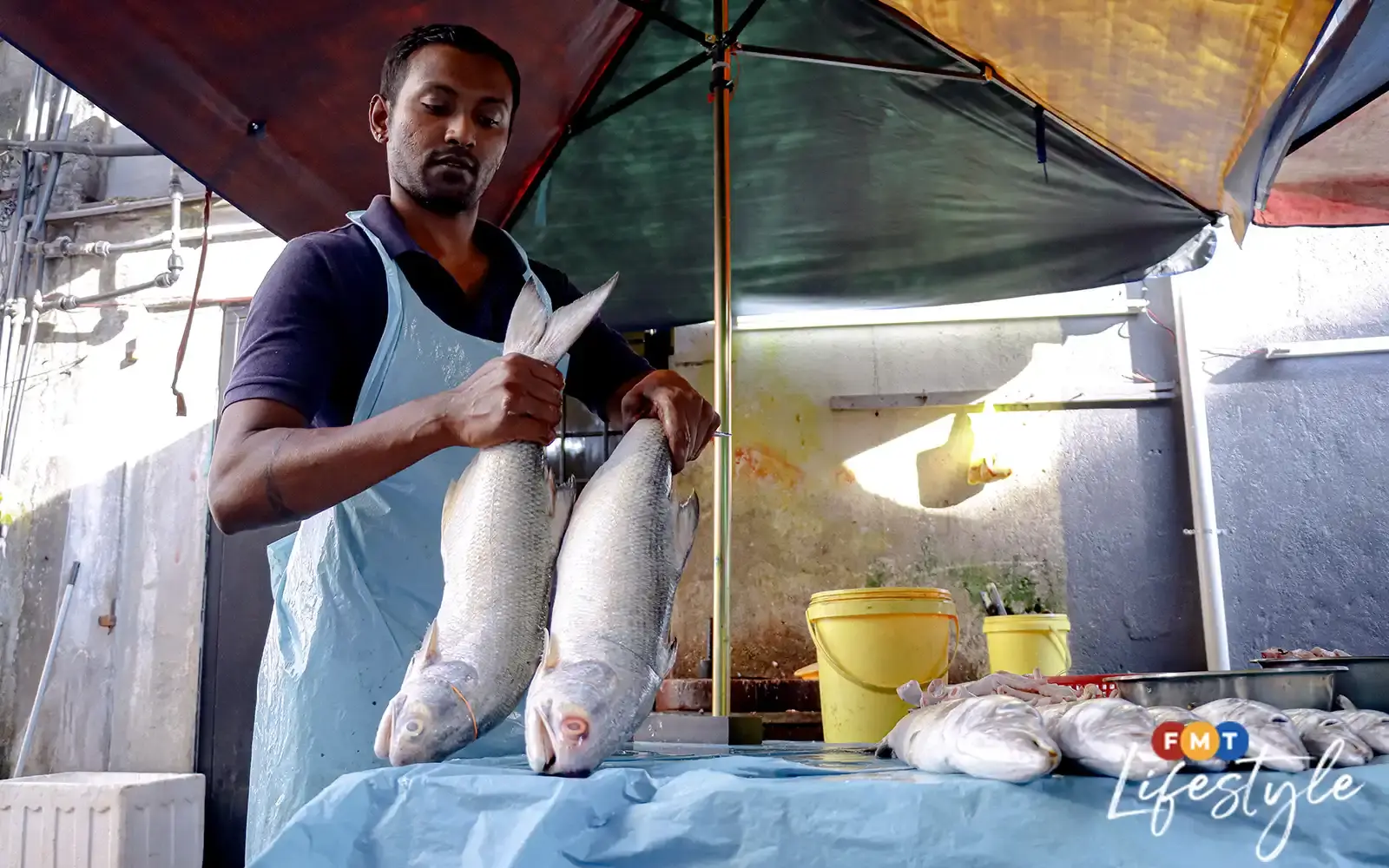 Fish seller holding two fish