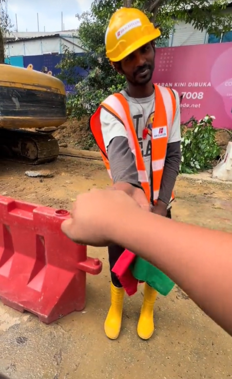M'sian man gives foreign worker money in the form of a fist bump