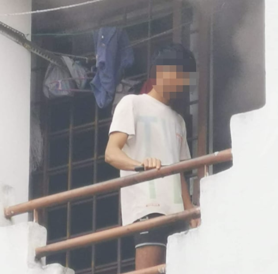 Foreign worker holding a knife while standing on the balcony