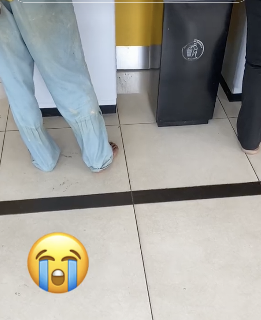 Foreign worker removes shoes at atm 01