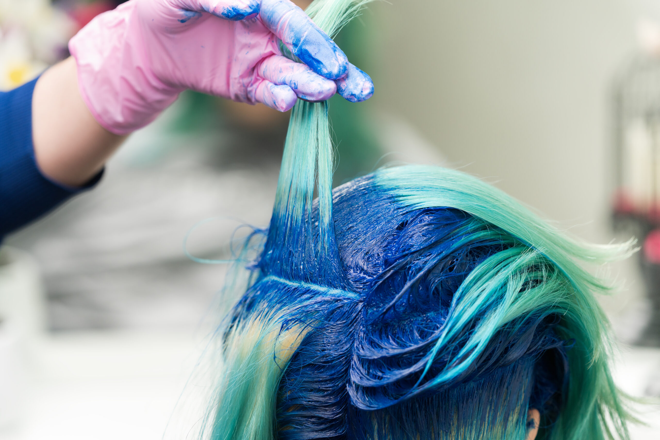 Hairdressers raise shock of blue hair of client during coloring process