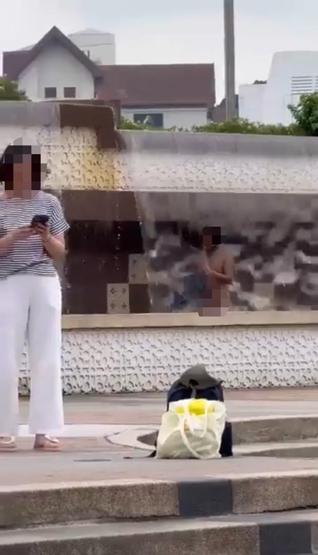 Homeless man washing his clothes inside a fountain at kl tourist spot