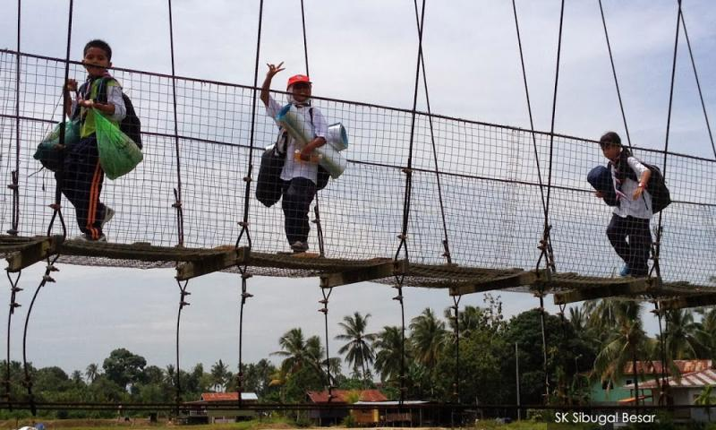 Keningau students precariously cross a river by using pipeline