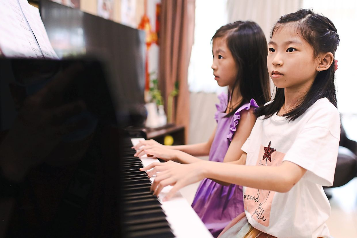 Ulrika lee yuen thong and felice lee ying theng playing the piano