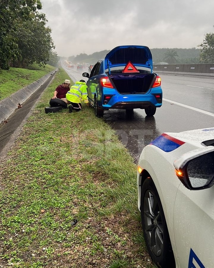 M'sian police officers praised for assisting stranded motorist with flat tire during heavy rain | weirdkaya