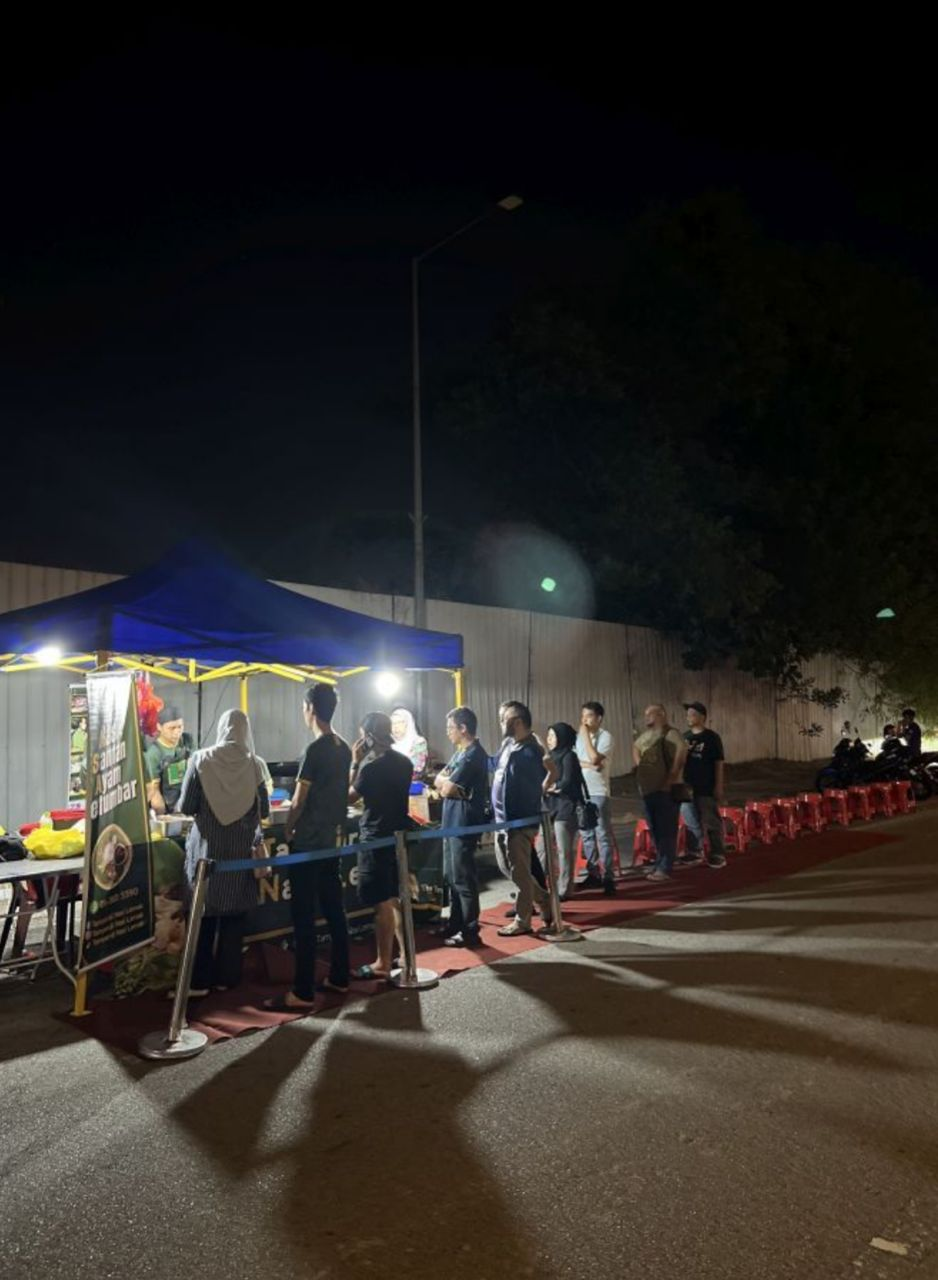 People waiting in line on a red carpet to buy street side food
