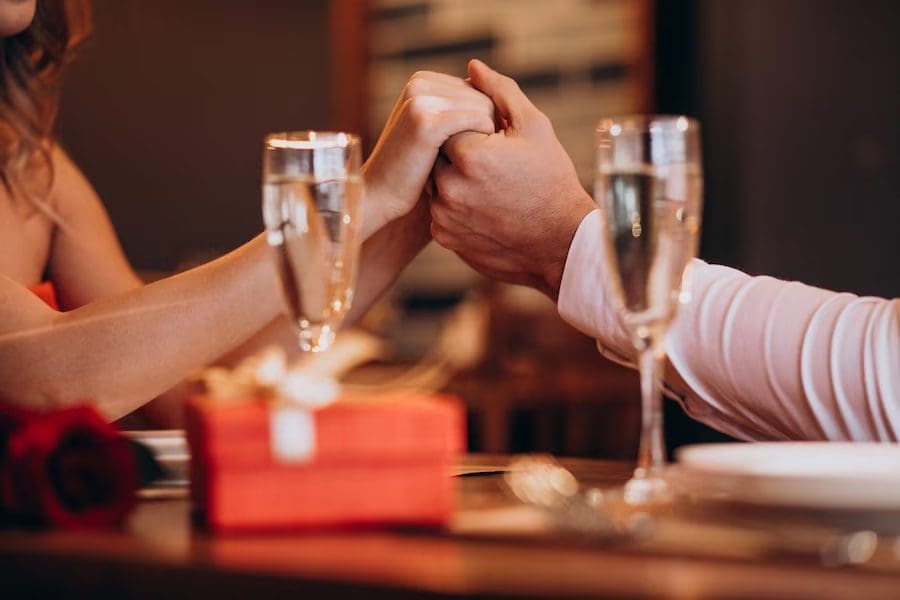 Couples holding hands and having wine together 