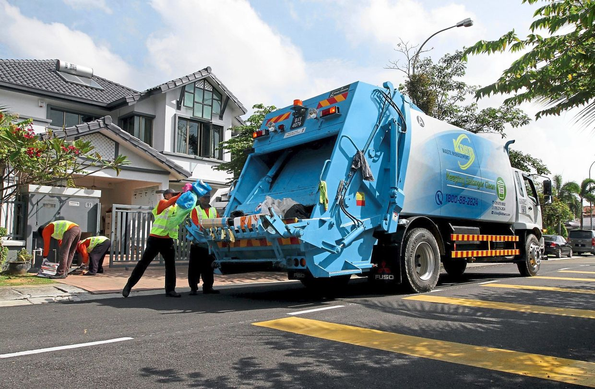 Garbage truck workers collecting trash and put them at the back