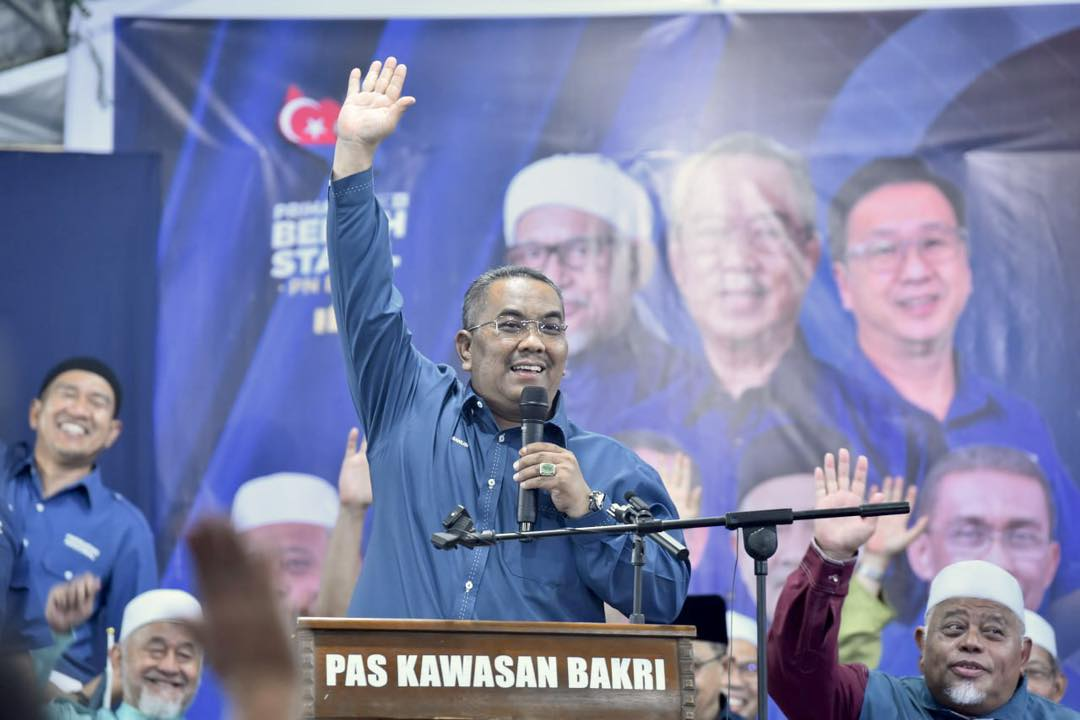 Kedah mb sanusi waving his hand at an event