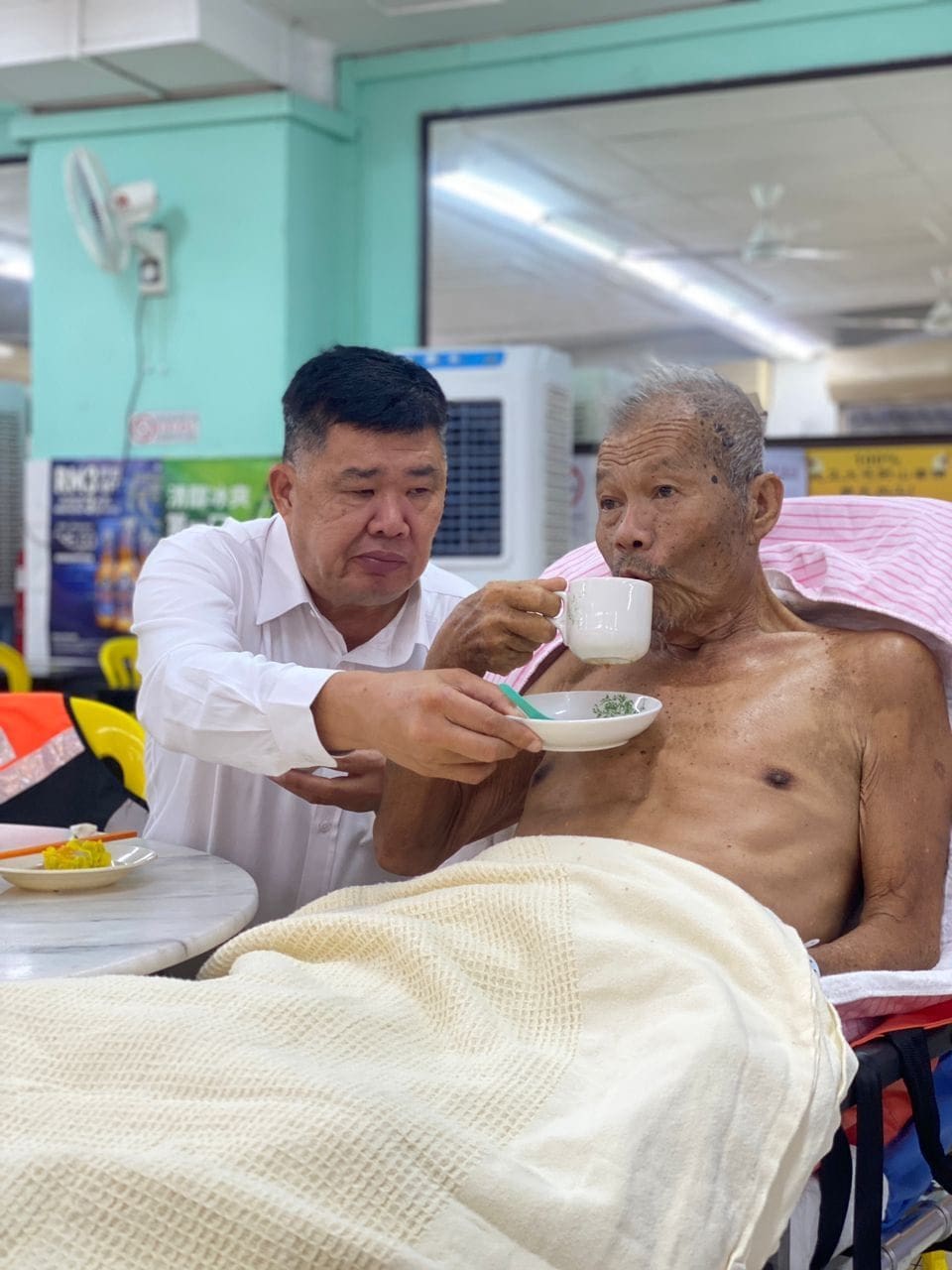 Uncle Kentang helps old man with a cup of tea