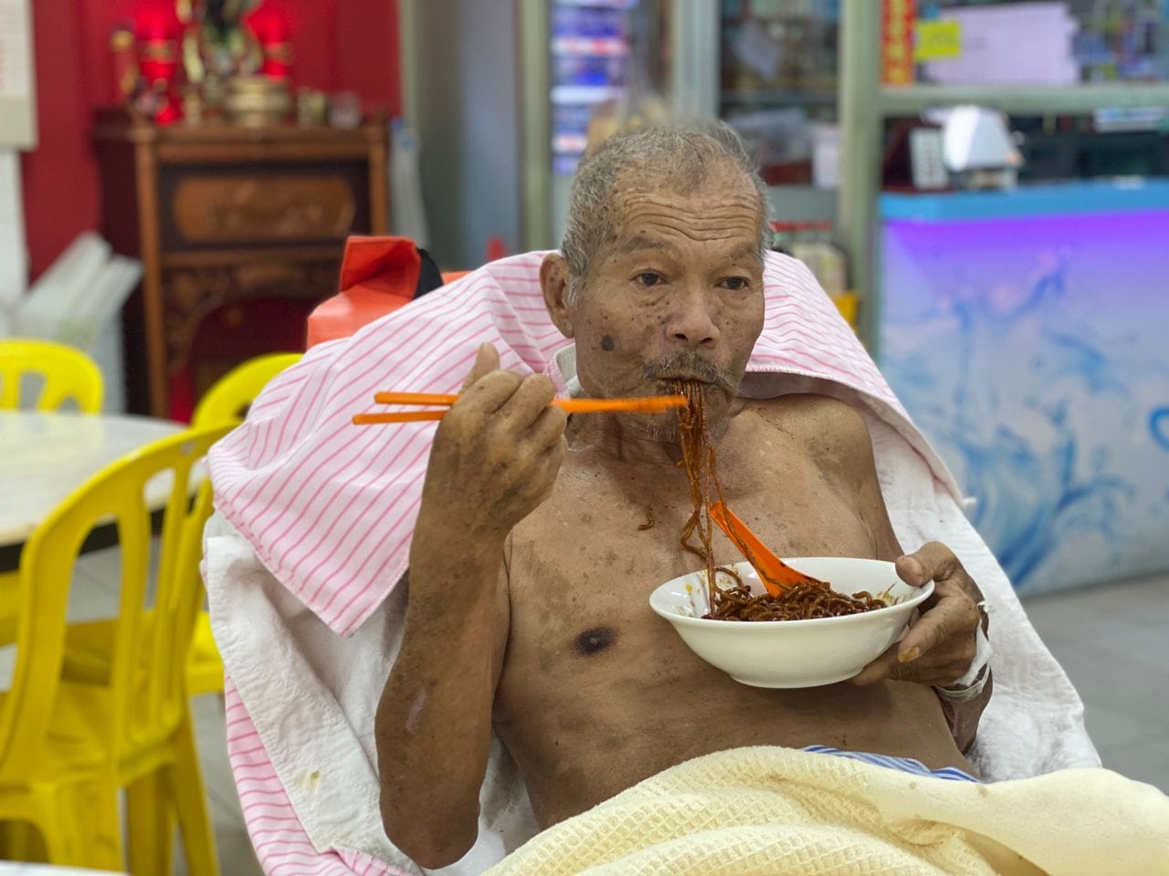 Old man eating a bowl of noodles
