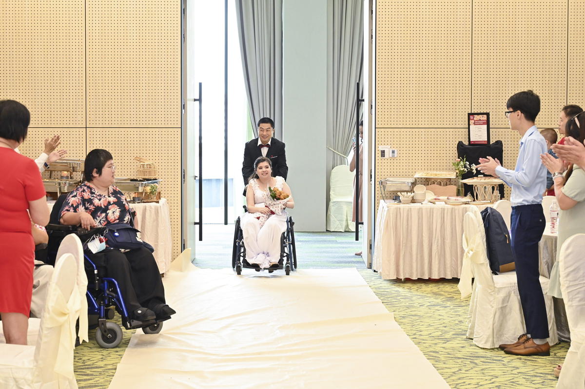 Xie Peng pushes Heather Wong down the aisle in her wheelchair