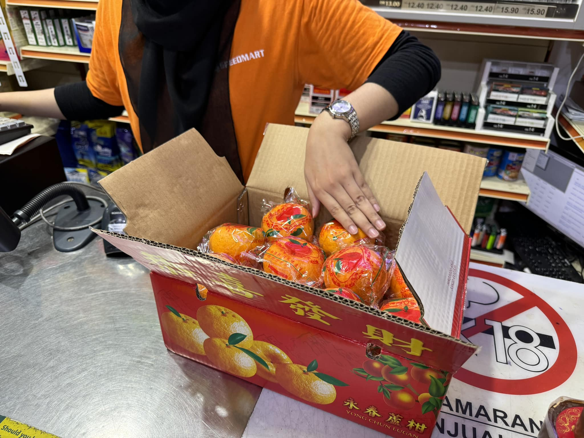 99 speedmart staff checks each mandarin oranges in box to check for spolied oranges