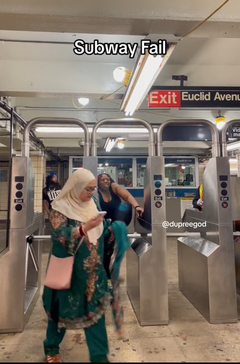Muslim woman and american at the subway's turnstile