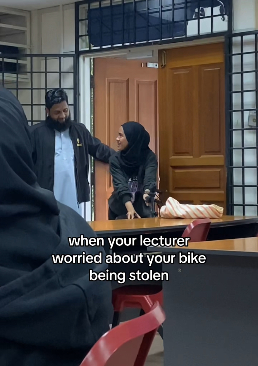 Dr. Aslam, lecturer at uia with a student who manoeuvres her bike into classroom