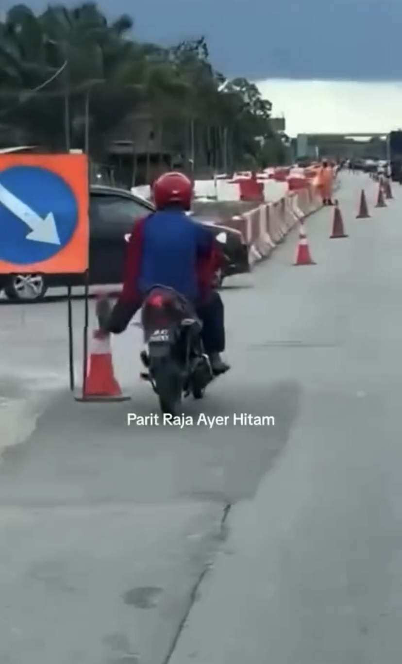 Motorcyclist kicking cones at the side of the road