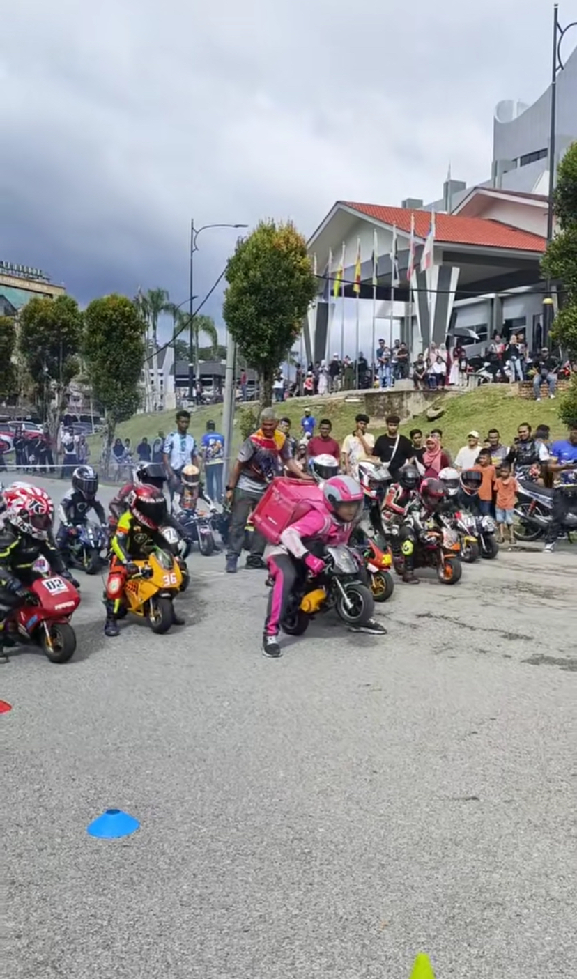 Bunch of kids dressed up as motor riders to race, and one is dressed up as a foodpanda rider
