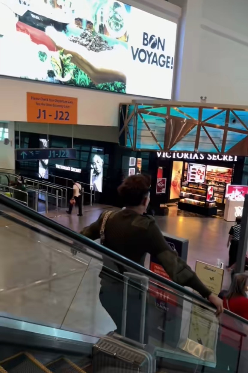 Man standing on escalator with luggage by his side in klia2