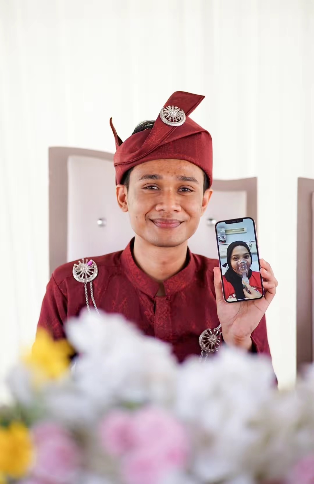 Malay man in a wedding ceremony holding a phone while video calling his wife who got hospitalised